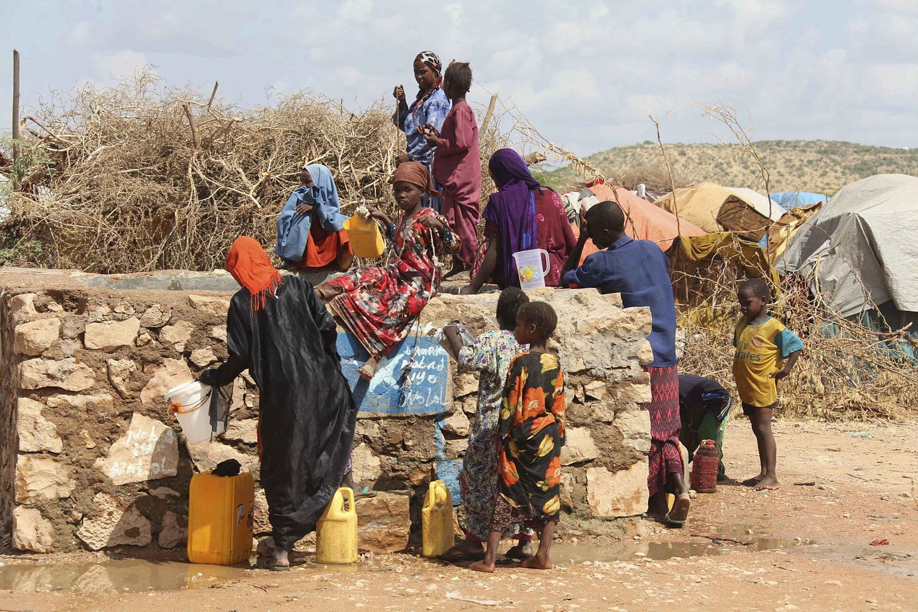 Women and children collecting water in jerrycans at a stone water tank